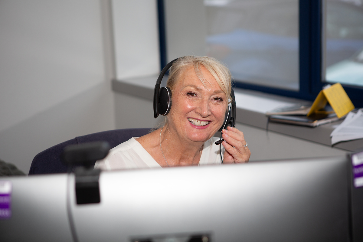sgp (1) Smiling woman wearing a headset in a radio studio at a workstation.