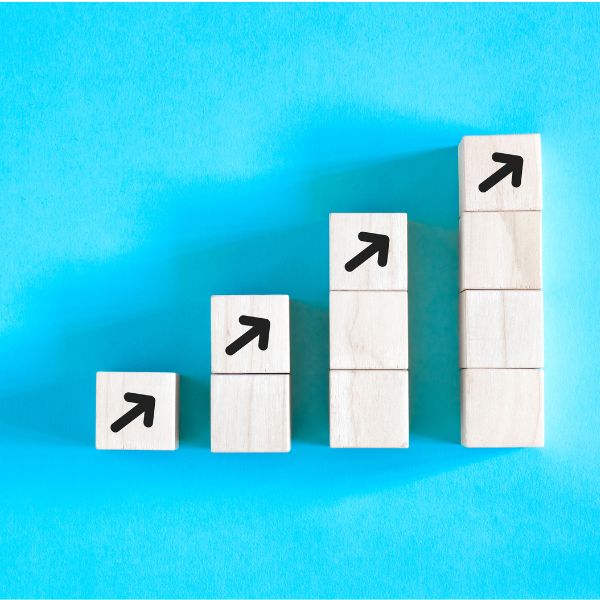 4 Wooden blocks stacked in four increasing steps with upward arrows against a blue background.